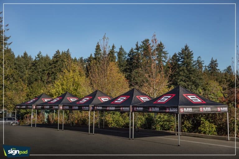 Set of black custom event tents with SLEGG branding in an outdoor parking lot.