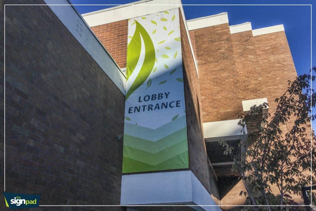 Exterior view of a large lobby entrance sign with green and white design.