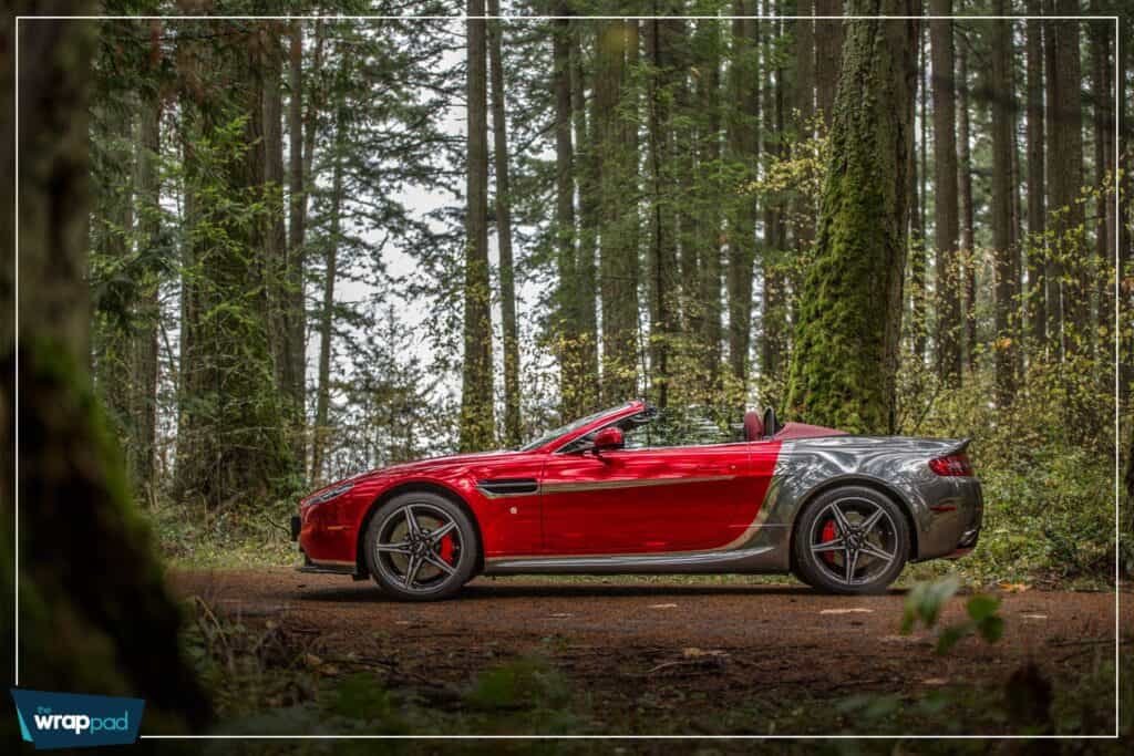 Sports car with custom wraps parked in a lush forest setting.