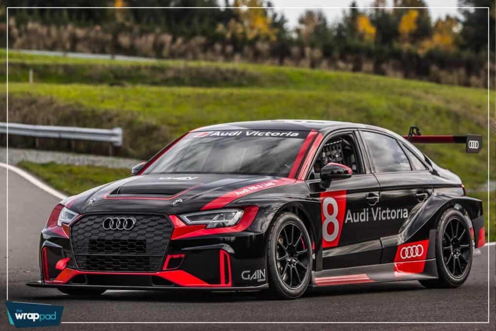 Race car with custom Audi Victoria wraps on a track.