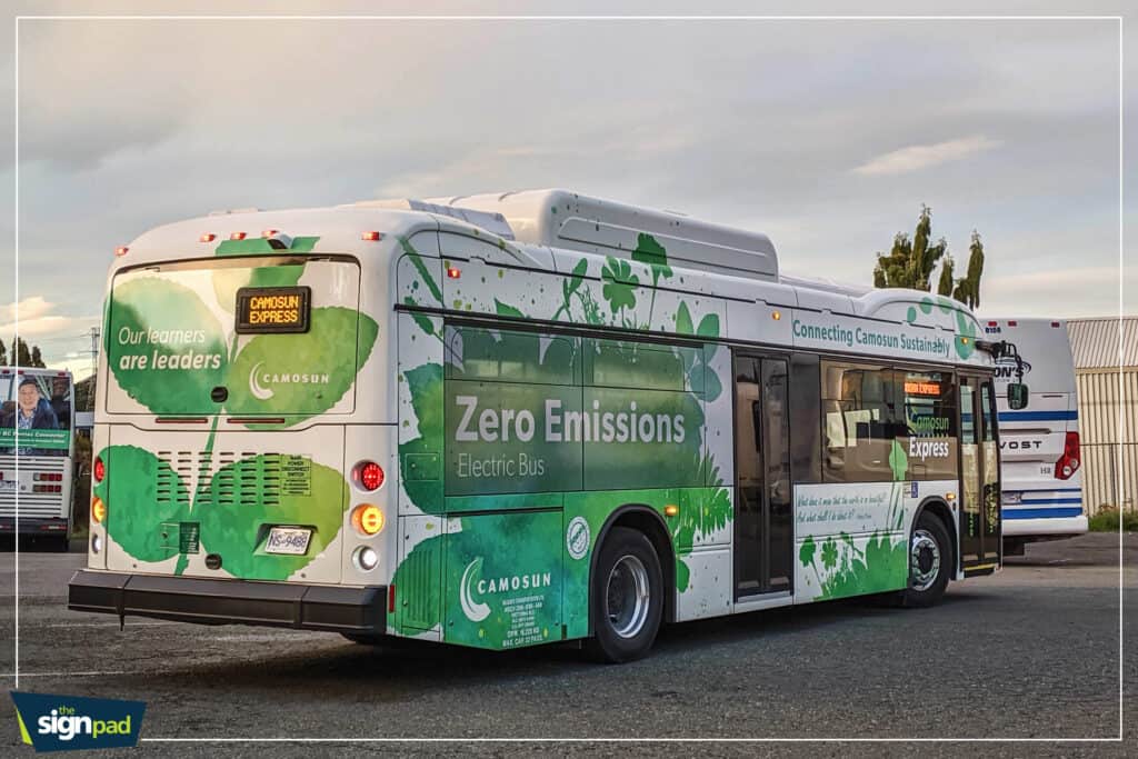 Eco-friendly electric bus with green leaf and tree graphics in Victoria.