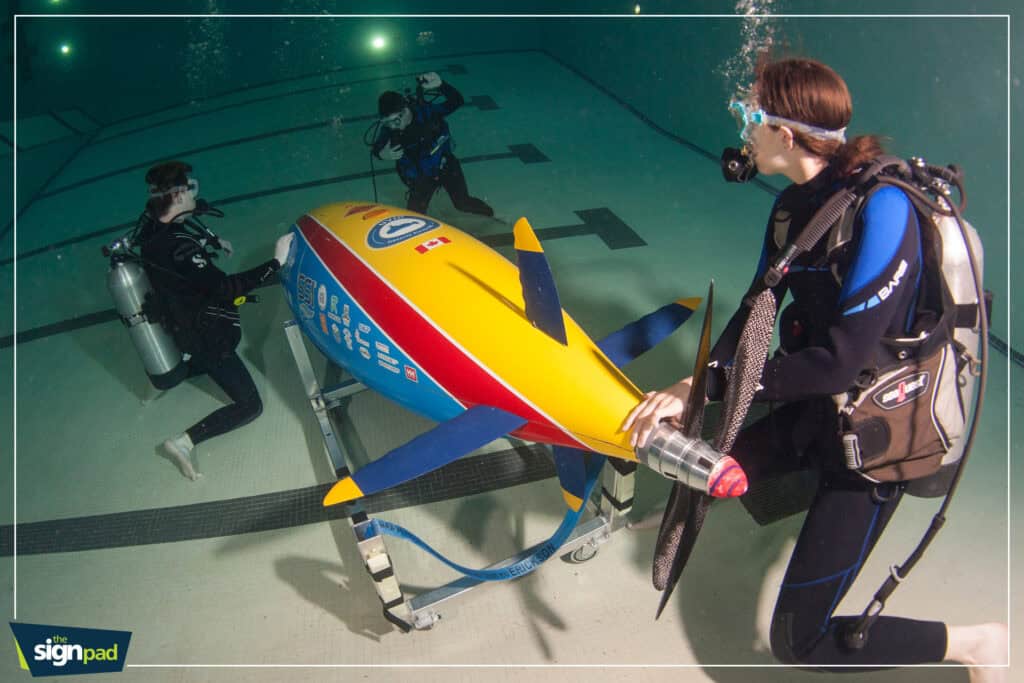An underwater scene showing a model submarine with divers practicing rescue techniques.