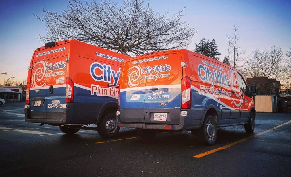 Two Citywide Plumbing service vans with custom wraps parked outdoors.