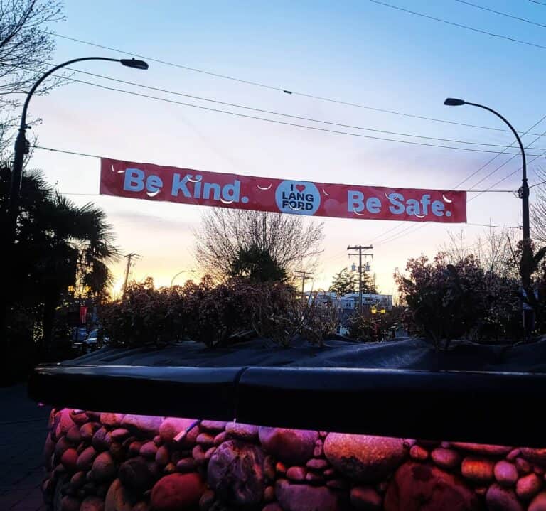 Outdoor banner with "Be Kind" and "Be Safe" messages in Victoria.