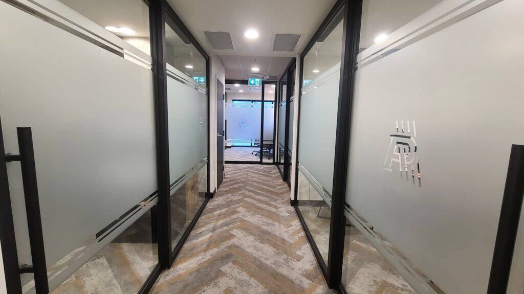 Office corridor with frosted glass partitions and modern design elements.