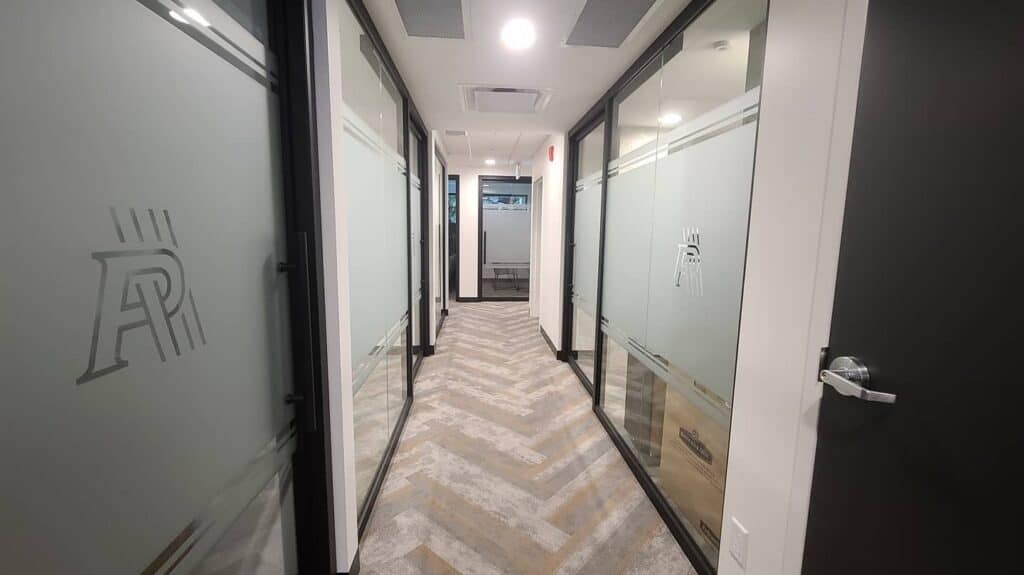 Modern office corridor with frosted glass doors and signage.