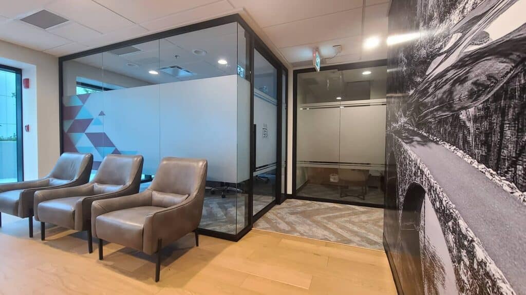 Office waiting area with glass partitions and cozy seating for visitors.