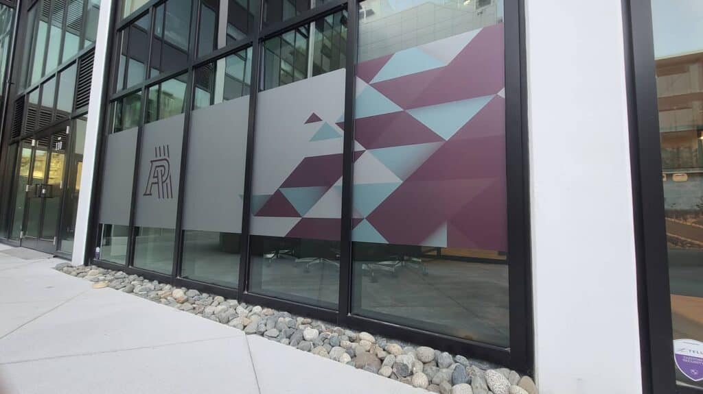 Custom geometric sign on glass facade for modern building in Victoria.