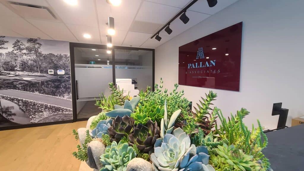 Digital sign reading "PALLAN ASSOCIATES" in a professional office setting.
