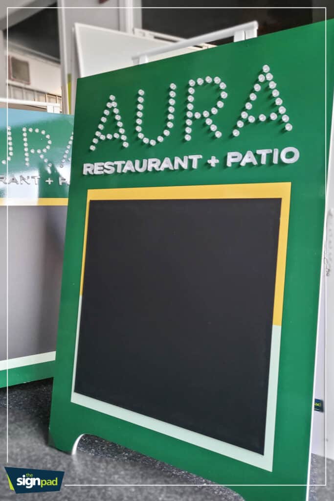 Custom green AURA restaurant and patio sign with chalkboard area for menus or specials.