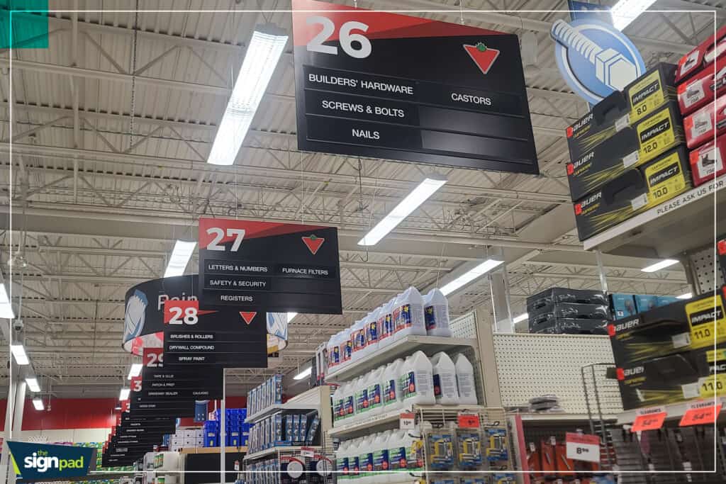 Signage displaying section numbers and product categories in a hardware store aisle.