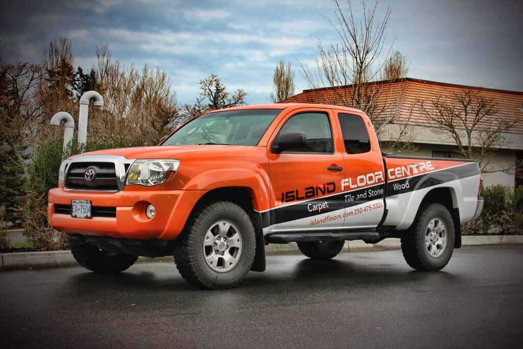 Bright orange truck with custom Island Floor vehicle wrap in Victoria.