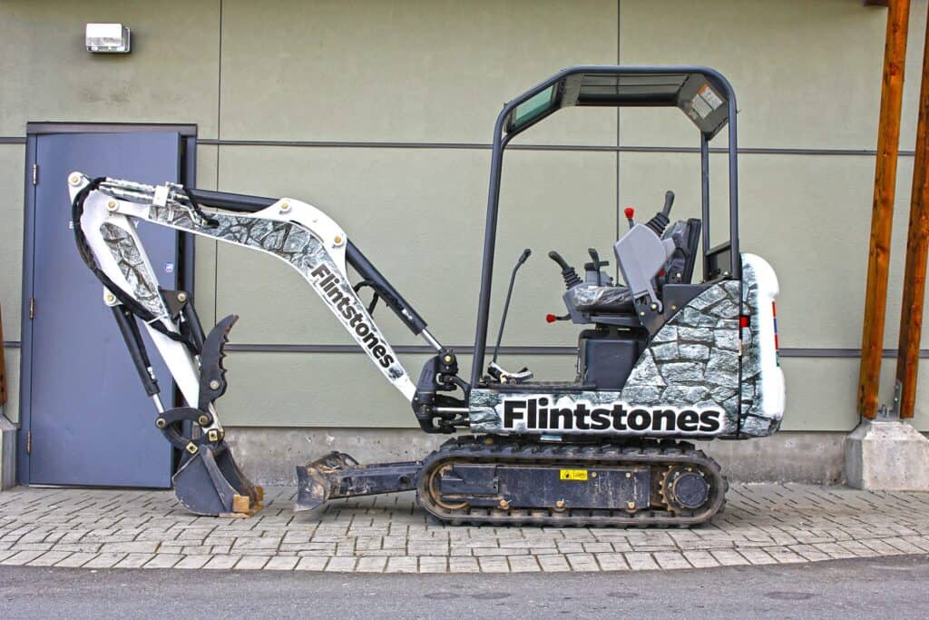 Mini excavator with custom vehicle wrap in Victoria, showcasing professional signage and branding.
