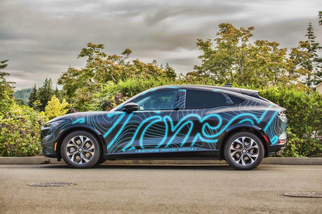 Custom vehicle wrap featuring neon blue graphics on a black SUV.