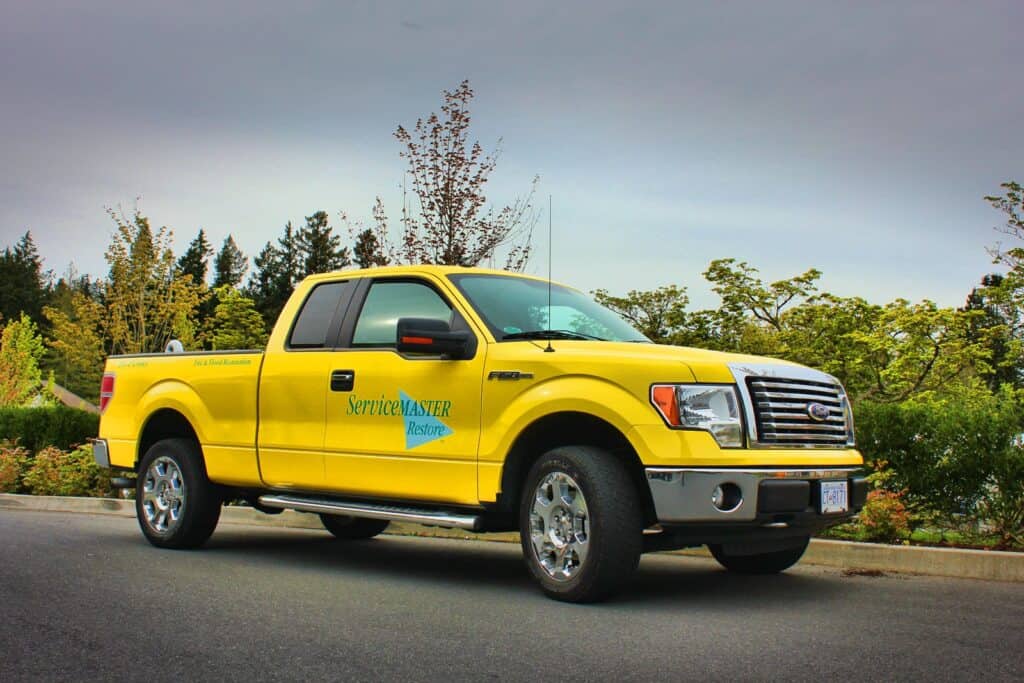 Custom yellow vehicle wrap for ServiceMaster Restoration on truck.