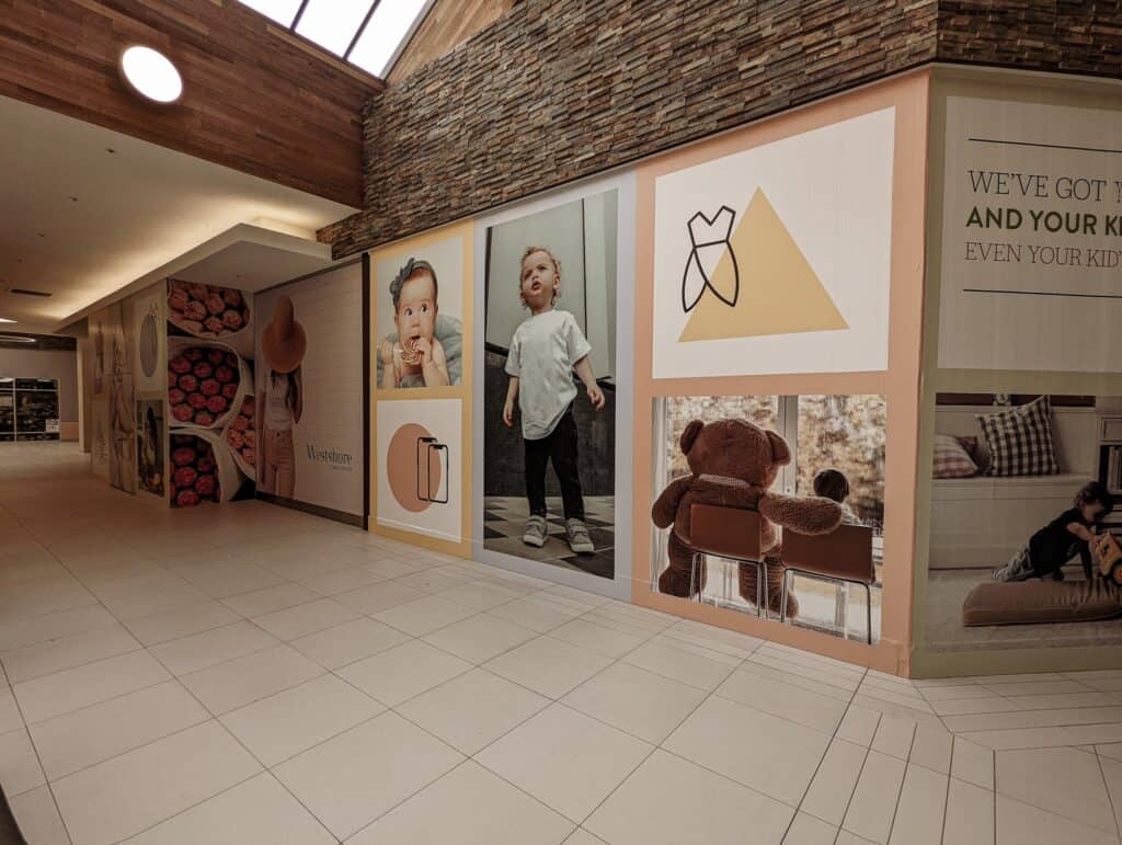 Children’s wall display with photos and custom signs in a shopping mall.