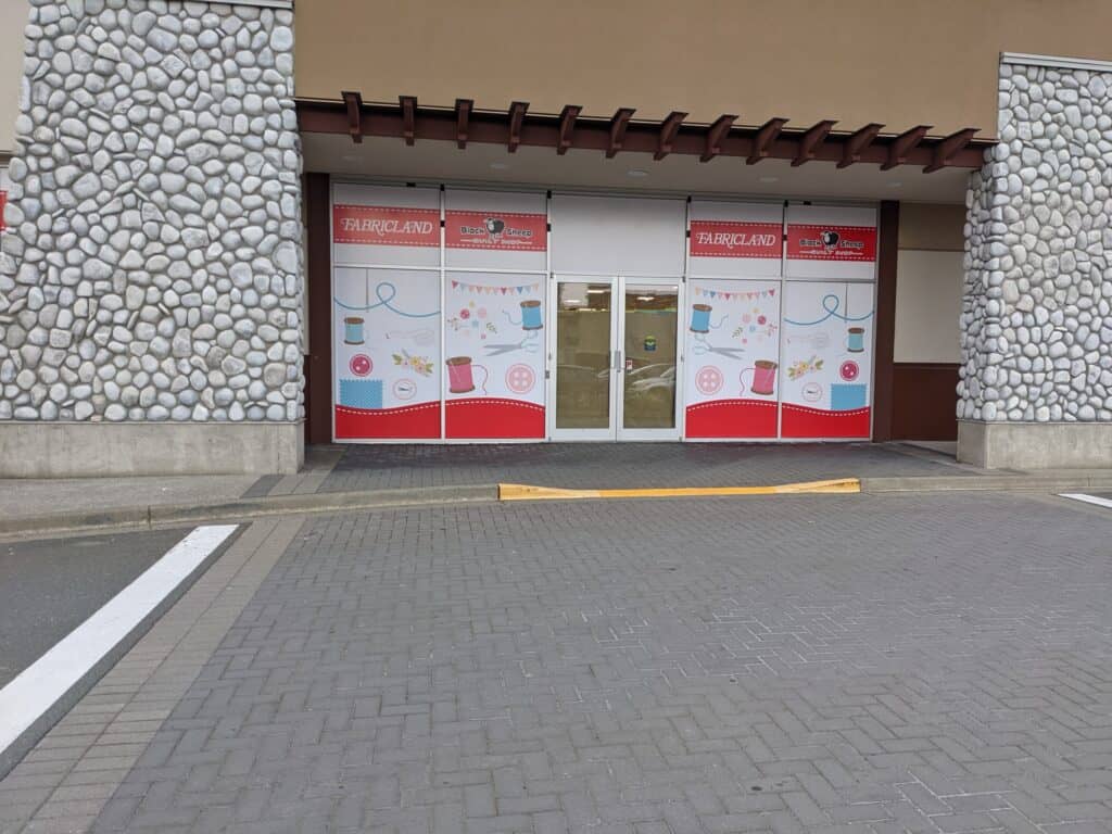 Custom Fabricland signage on store entrance with colorful fabric patterns and branding.