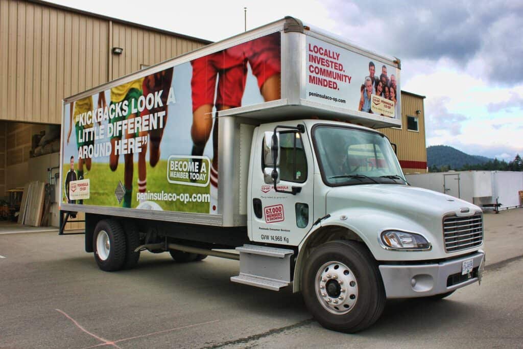 Community outreach truck with vibrant custom signs promoting local investment and community involvem.