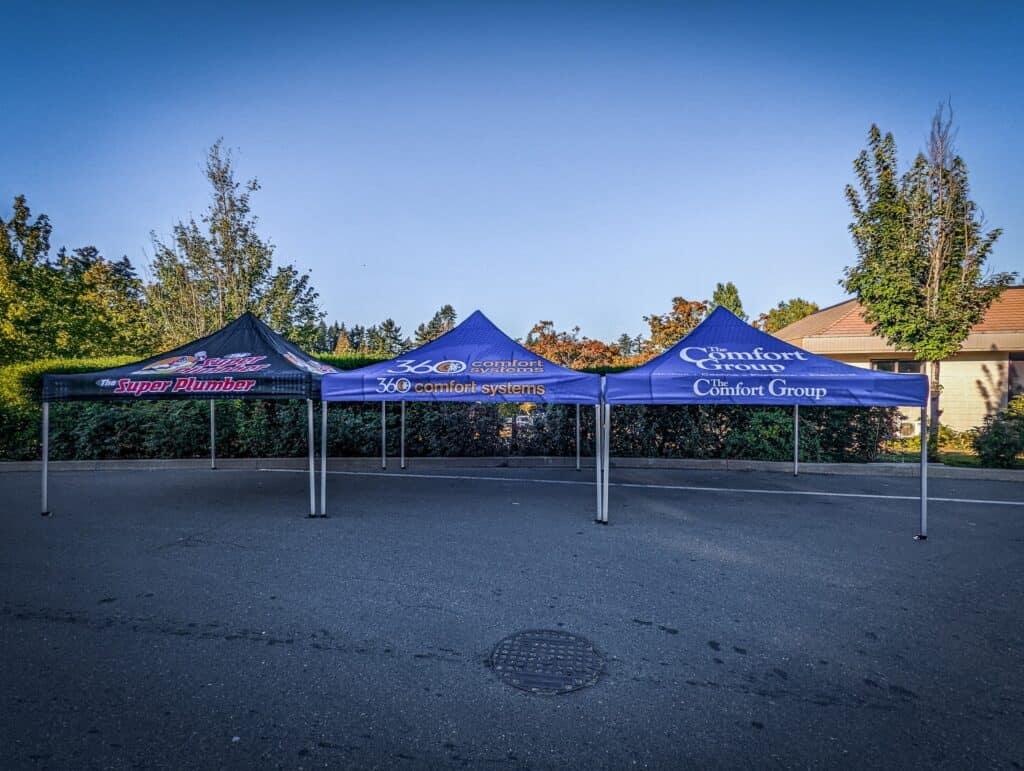 Three custom canopy tents with branding for Comfort Group and Superior Plumbing at an outdoor event.