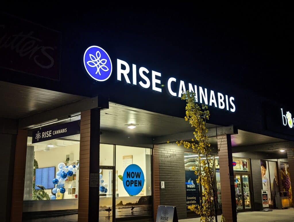 Exterior view of Rise Cannabis storefront with illuminated sign at night.