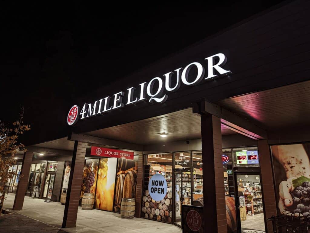 4 Mile Liquor Store illuminated sign at night.