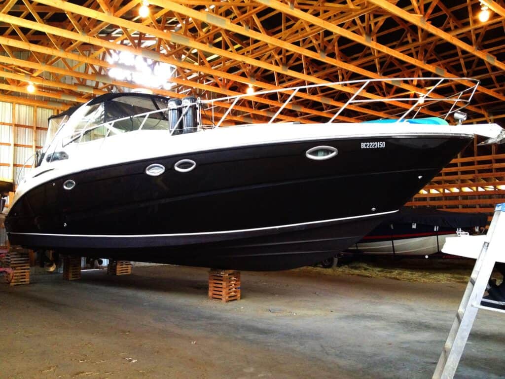 Luxury black yacht displayed indoors on wooden supports.