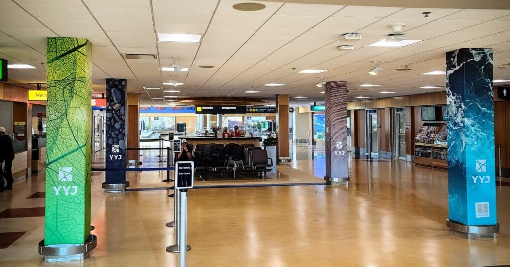 Colorful signage pillars at airport terminal with seating and check-in counters.