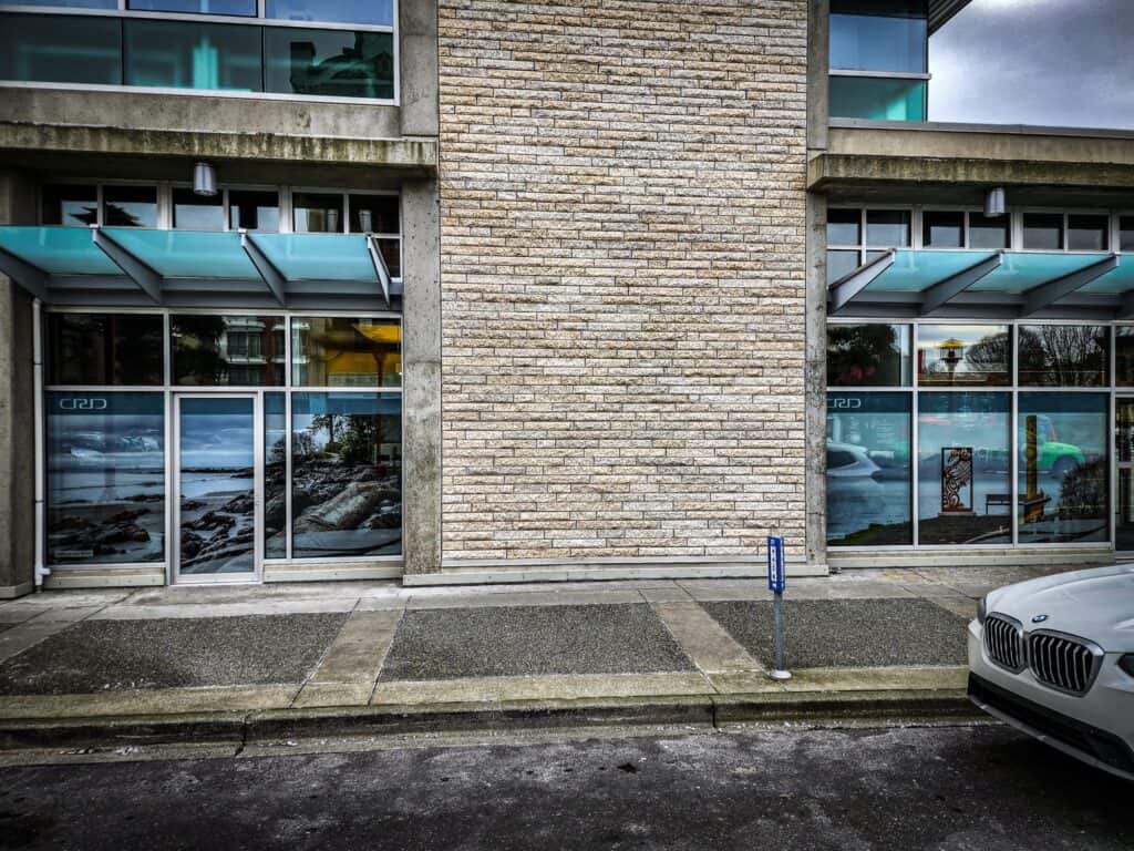 Modern commercial building with glass storefronts and a brick central wall.