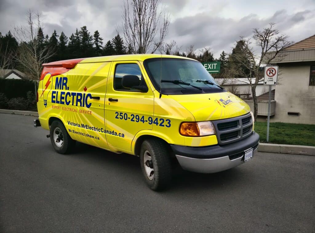 Bright yellow Mr. Electric service van parked on the street.