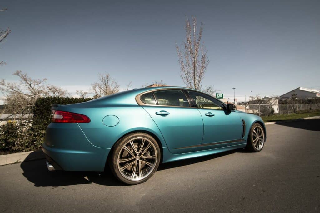 A sleek blue luxury sedan parked outdoors on a sunny day.