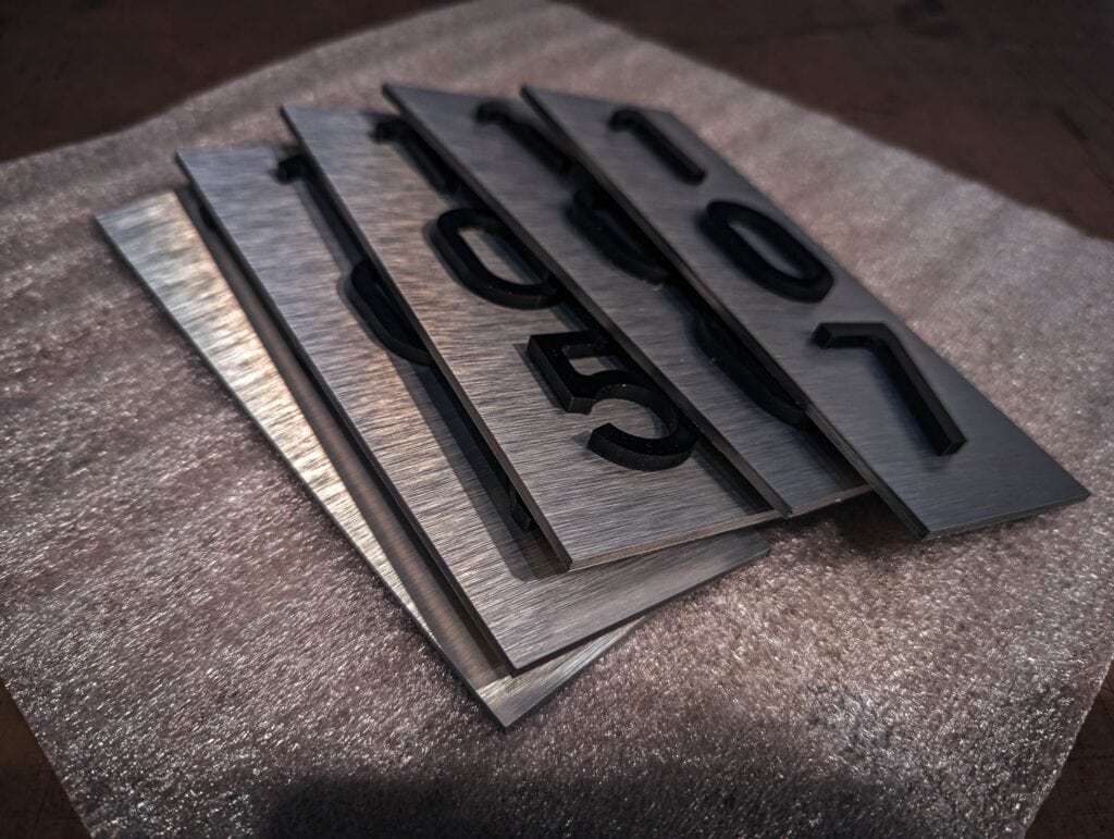 Custom metal sign plates with engraved numbers for signage and vehicle wraps.