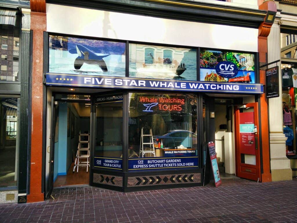 Whale watching tour sign on storefront with CVS and Five Star Whale Watching.