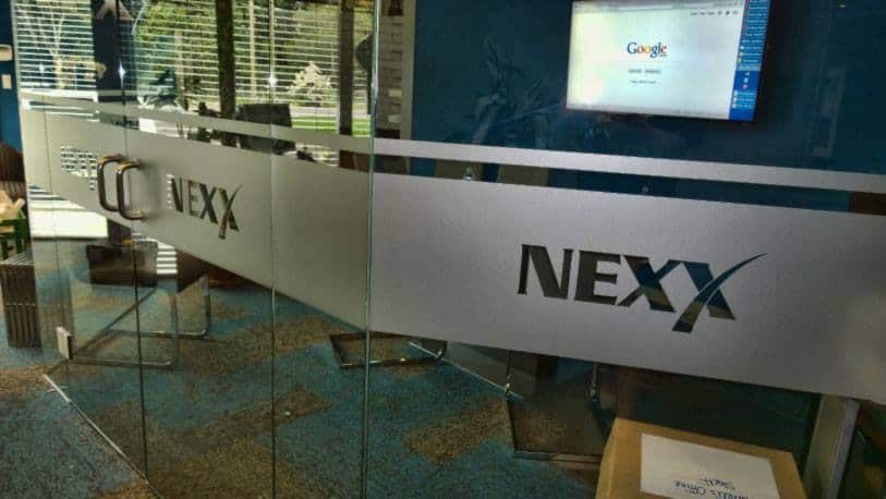Modern NEXX sign on glass wall at Victoria office.