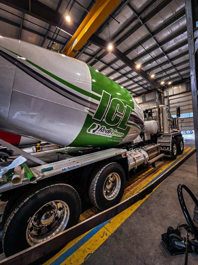 Fuel tank vehicle wrap with green and white design, displayed inside a warehouse.
