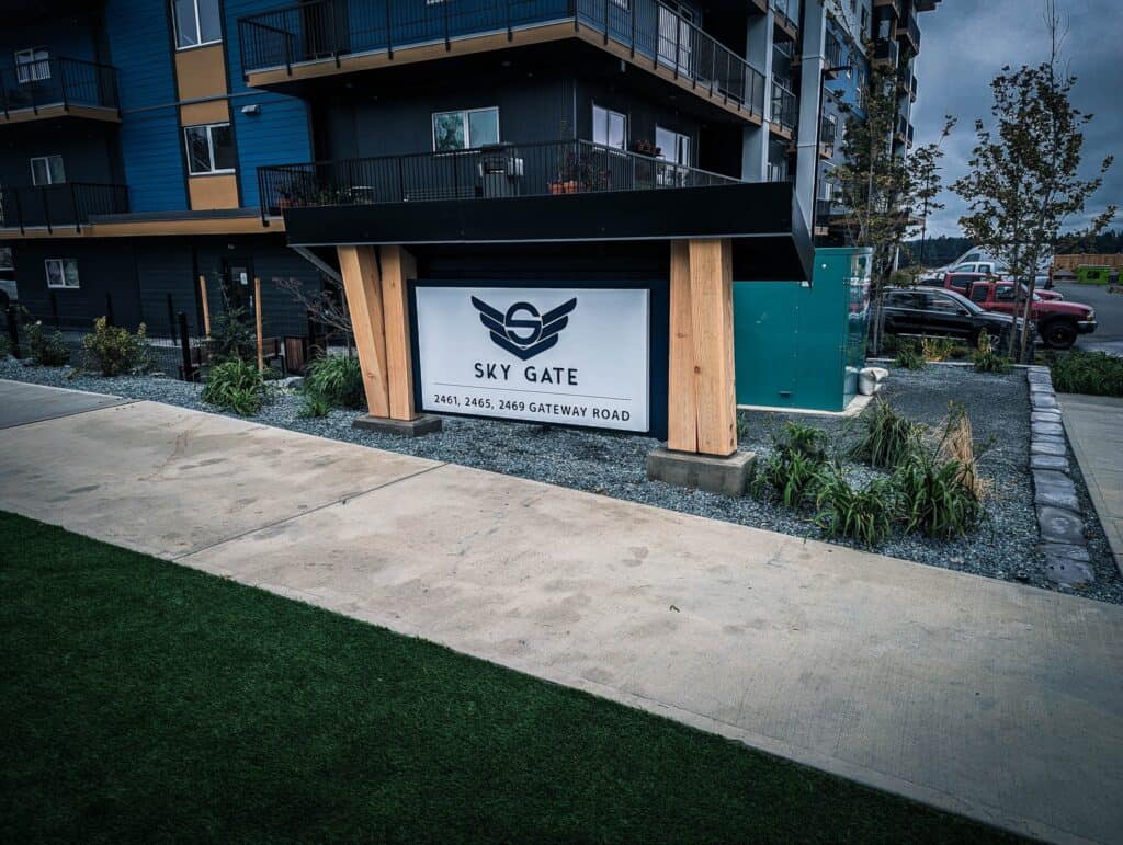 Modern residential complex sign with Sky Gate logo and address details.