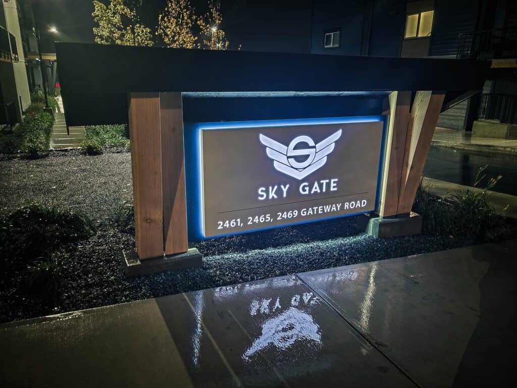 Illuminated outdoor sign for Sky Gate with logo and address.