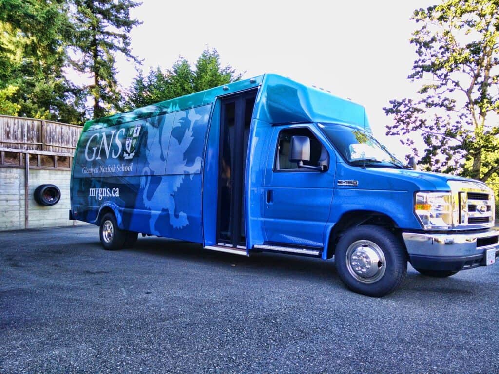 School bus with vibrant blue wrap promoting GNSL and their website.