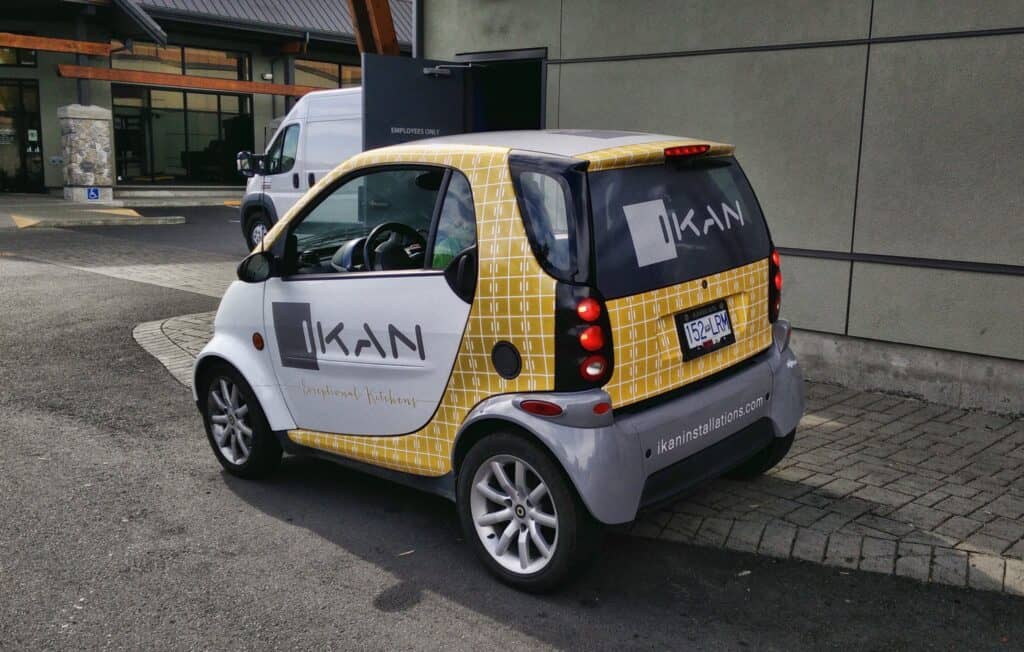 Compact electric vehicle with IKAN branding and custom signage wrap in Victoria.