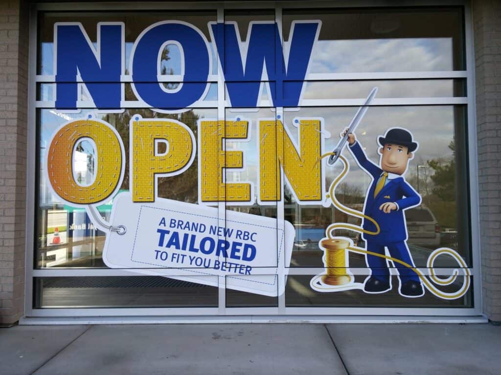 Window sign with "Now Open" and a cartoon tailor character.