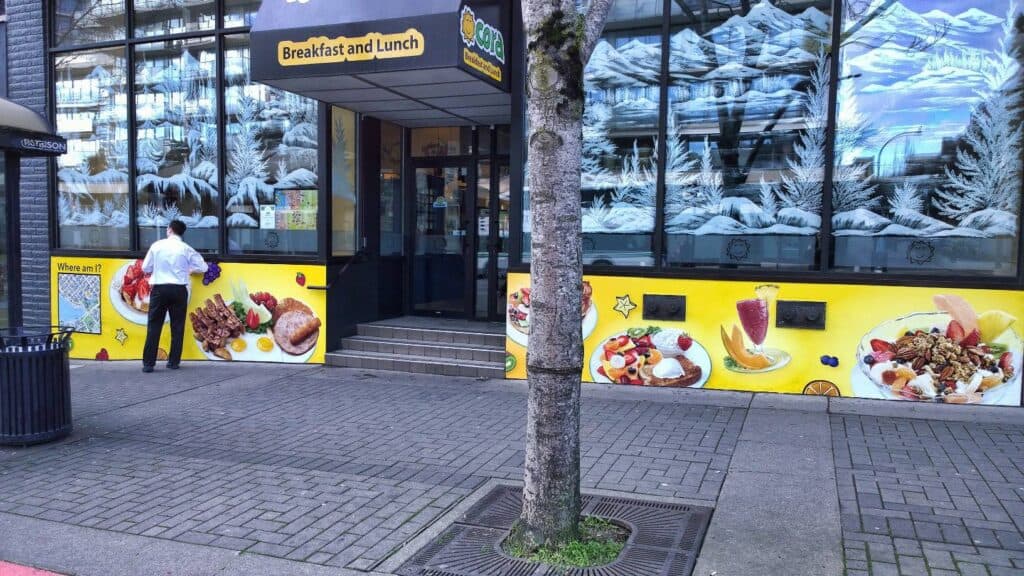 Bright yellow breakfast and lunch restaurant sign with food images in Victoria.