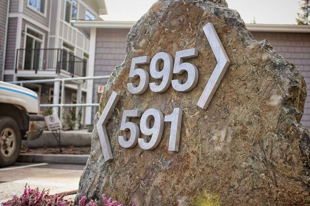 Custom stone address sign with house numbers 595 and 591 and directional arrows.