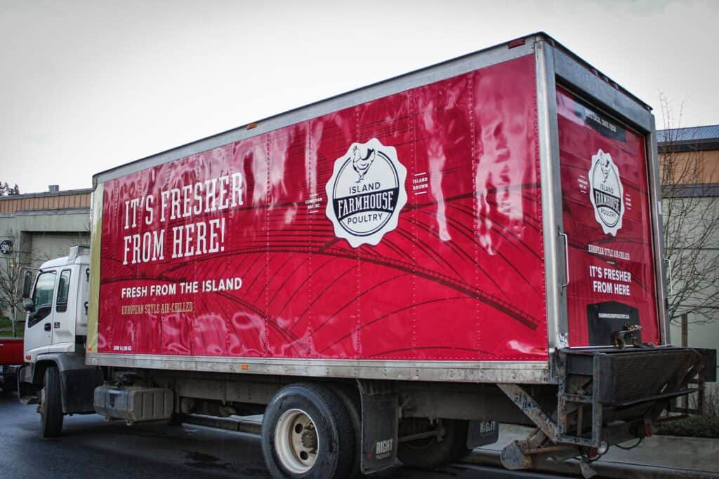 Red delivery truck with Island Farmhouse Poultry branding and slogan.