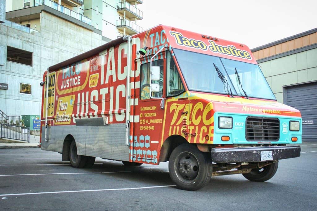 Colorful Taco Justice food truck with vibrant branding in an urban setting.