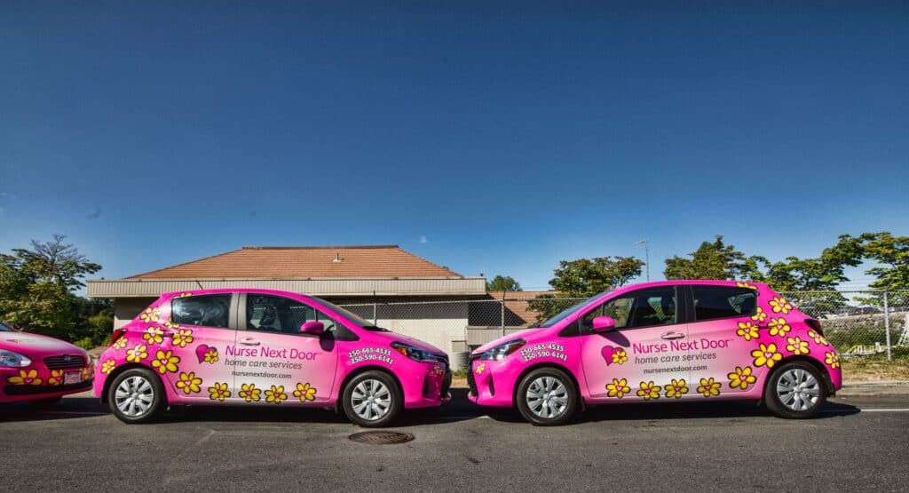 Two pink cars with floral vehicle wraps for Nurse Next Door in Victoria.