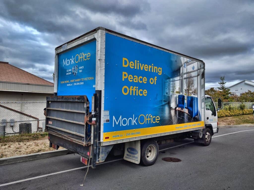 Moving office truck with vibrant blue and yellow custom signage for Monk Office in Victoria.