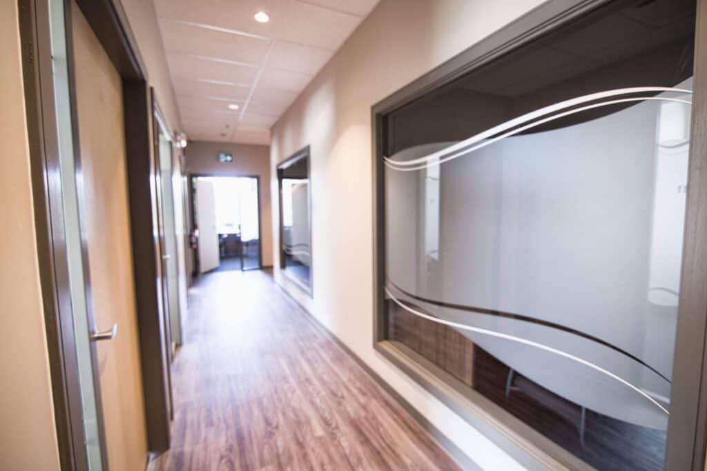 Modern office corridor with large glass sign pad and wooden flooring.