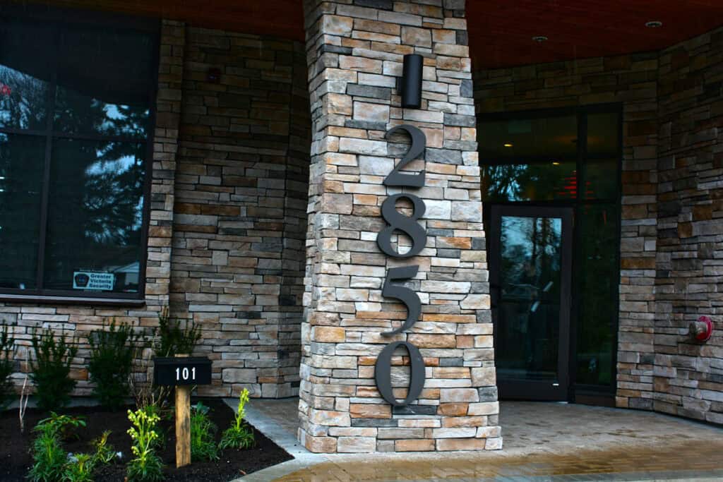 Signage with Address Numbers on Exterior Stone Wall.