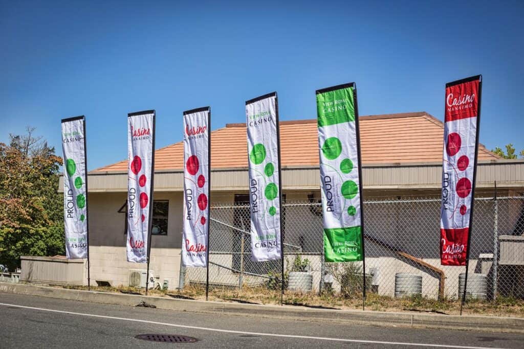 Colorful casino promotional flags displayed outside a building in Victoria.
