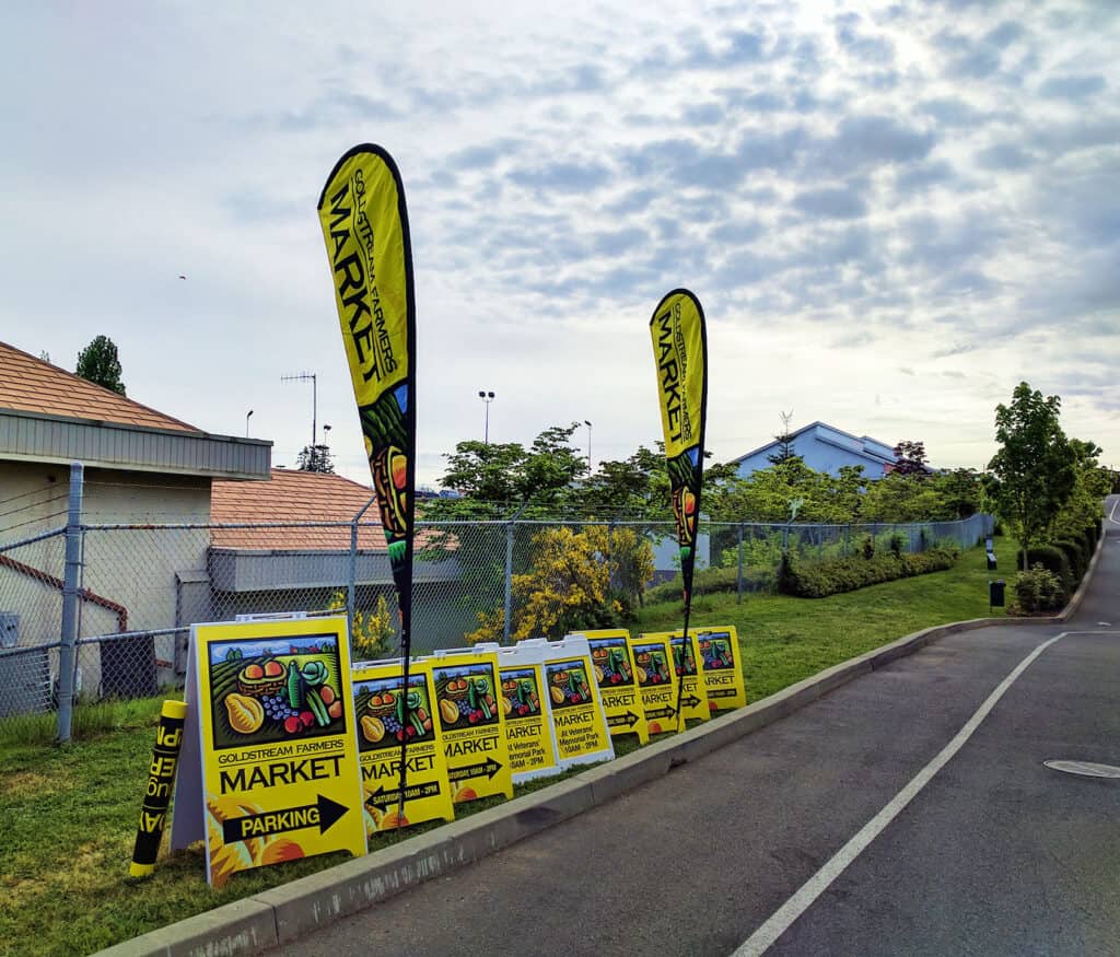 Outdoor market signs with flags and boards along the street.