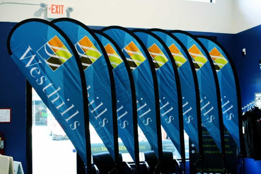 Set of blue promotional flags with Westhill logo indoors.